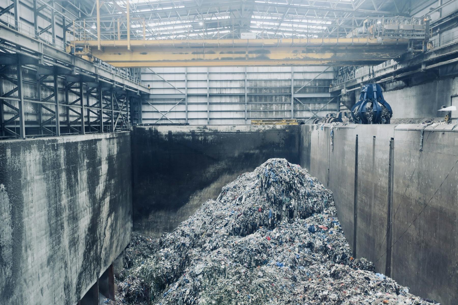 An energy-from-waste tipping hall, with a grab crane above the feedstock.